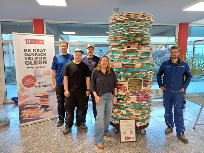 Fünf Personen vor einem Bücherturm im Verwaltungsgebäude der Buchhandlung Tyrolia in Innsbruck