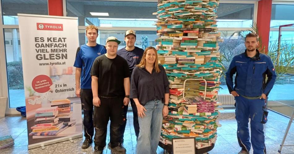 Vier Personen im Verwaltungsgebäude der Buchhandlung Tyrolia vor dem Bücherturm